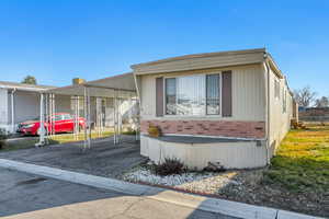 Manufactured / mobile home featuring a carport, brick siding, and asphalt driveway
