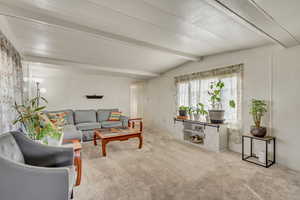 Living area featuring light carpet and vaulted ceiling with beams