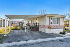 Manufactured / mobile home featuring an attached carport, covered porch, and brick siding