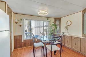 Dining space featuring wooden walls, a wainscoted wall, and light wood-style floors