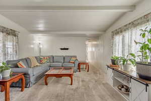 Living area with carpet floors and beamed ceiling