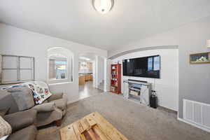 Living area with carpet flooring, arched walkways, and a textured ceiling