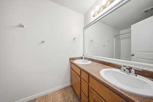 Full bath with double vanity, a shower, and light tile patterned floors