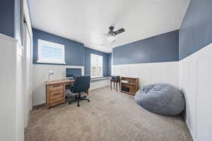 Office space with ceiling fan, a wainscoted wall, carpet floors, a decorative wall, and a textured ceiling
