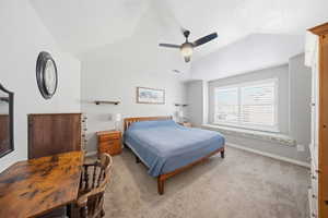Carpeted bedroom featuring vaulted ceiling and a ceiling fan