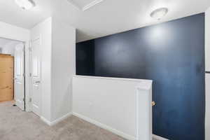 Corridor with an upstairs landing, carpet, and a textured ceiling