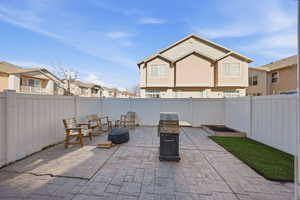 Fenced backyard with a residential view, a patio area, a fire pit, and grilling area