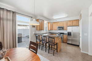 Kitchen with decorative light fixtures, stainless steel appliances, a breakfast bar area, tasteful backsplash, and a peninsula