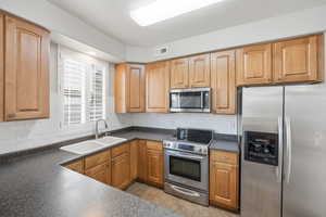 Kitchen featuring stainless steel appliances, backsplash, and dark countertops