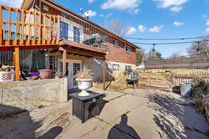 Rear view of property featuring basement walkout french doors, a patio, a balcony, brick siding, and a wooden deck
