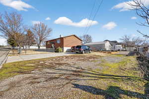 View of property exterior featuring a chimney, concrete driveway, and brick siding