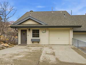 View of front of home with a shingled roof, driveway, and stucco siding