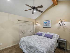Bedroom featuring lofted ceiling with beams, dark carpet, a closet, and a ceiling fan