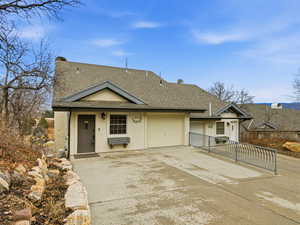 View of front of property featuring a shingled roof, driveway, stucco siding, and a garage