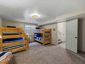 Carpeted bedroom featuring a textured ceiling and baseboards