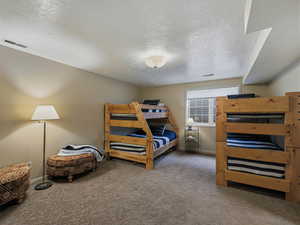 Carpeted bedroom with a textured ceiling and baseboards
