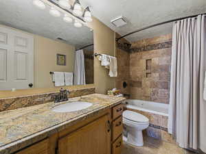 Bathroom with vanity, tiled shower / bath combo, and a textured ceiling