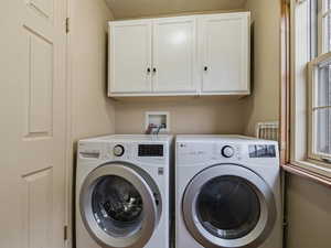 Laundry area featuring cabinet space, independent washer and dryer, and a textured ceiling