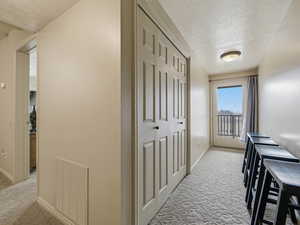 Corridor with a textured ceiling and light carpet