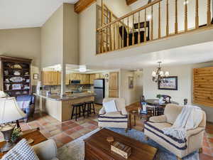 Living room featuring suspended lighting, lofted ceiling, and light tile patterned flooring