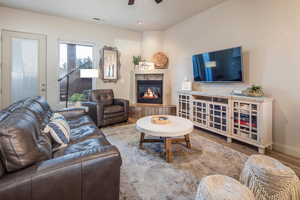 Living room with a ceiling fan, wood finished floors, and a tiled fireplace