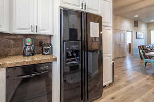 Kitchen with black appliances, light wood-style flooring, white cabinetry, recessed lighting, and tile countertops