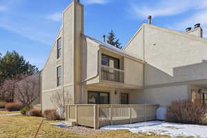 Back of property with a chimney, a balcony, and stucco siding
