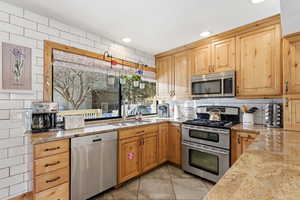 Kitchen with stainless steel appliances, light stone countertops, and recessed lighting