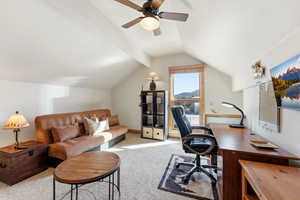 Home office featuring light carpet, a ceiling fan, and beamed ceiling