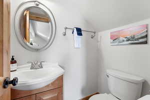 Half bathroom with vanity and vaulted ceiling