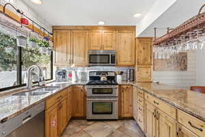Kitchen featuring light stone counters, stainless steel appliances, recessed lighting, and backsplash