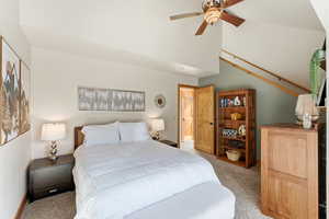 Carpeted bedroom with a ceiling fan and a high ceiling