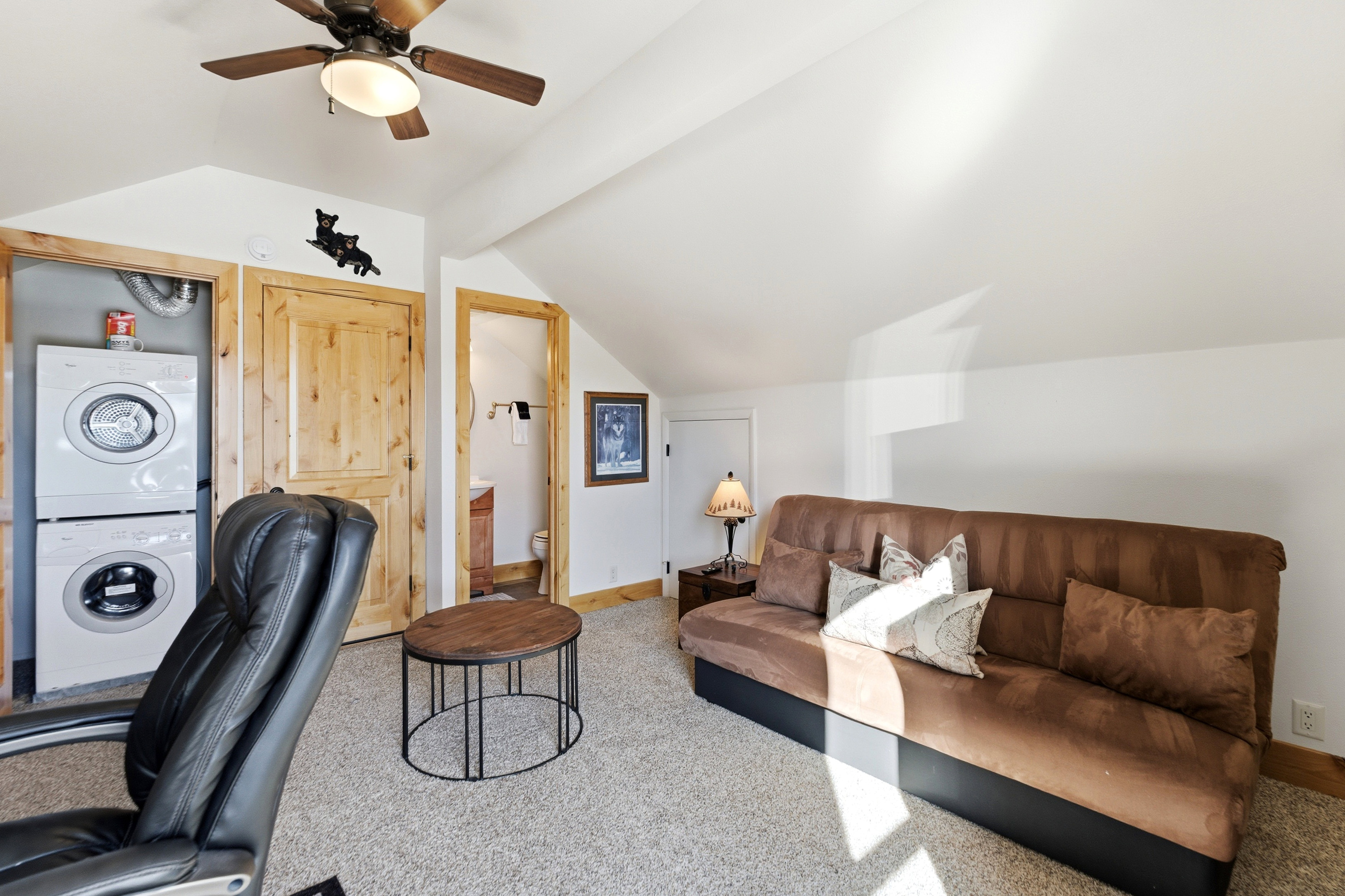 Office space with lofted ceiling, carpet flooring, stacked washer / dryer, and ceiling fan