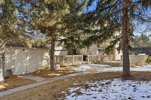 Snow covered rear of property with stucco siding and a deck