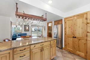 Kitchen featuring light stone countertops, stainless steel refrigerator with ice dispenser, light tile patterned flooring, open floor plan, and recessed lighting