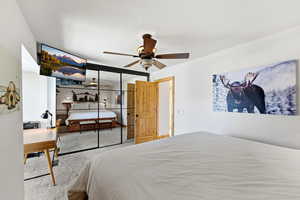 Carpeted bedroom featuring ceiling fan and a closet
