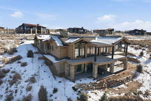 Snow covered house featuring stone siding, a residential view, and a patio