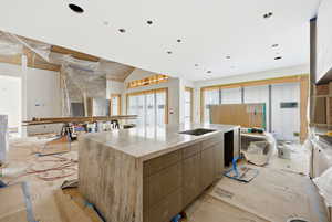 Kitchen featuring light stone counters, an island with sink, modern cabinets, and open floor plan