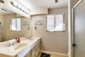 Bathroom featuring double vanity, healthy amount of natural light, and a shower with door