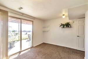 Carpeted spare room with a textured ceiling and baseboards