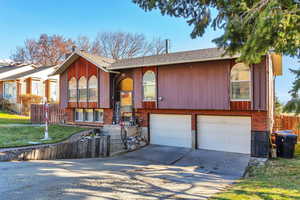 Split foyer home featuring a garage, concrete driveway, brick siding, and roof with shingles