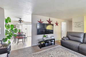 Living area with carpet floors, a textured ceiling, and ceiling fan