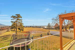 Fenced backyard with a trampoline and a view of rural / pastoral area