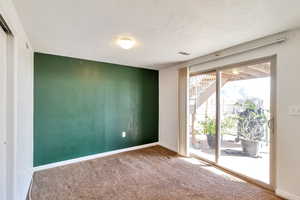 Carpeted spare room with a textured ceiling and an accent wall