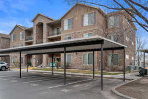 View of property with stairway and covered parking