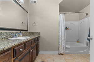 Bathroom with shower / bath combination with curtain, vanity, and light tile patterned floors