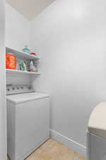 Laundry room with light tile patterned floors and washing machine and clothes dryer