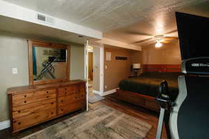 Bedroom featuring dark wood finished floors, a textured ceiling, and a ceiling fan