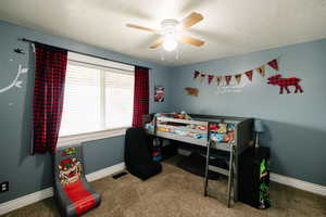 Bedroom with carpet flooring, a ceiling fan, and a textured ceiling