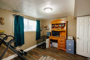 Office area featuring a textured ceiling and dark wood-style floors
